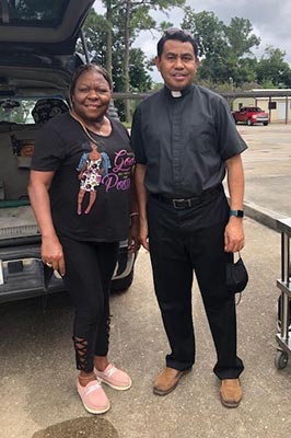 Fr. Lambert Lein, SVD standing with a female parishioner near a car. 