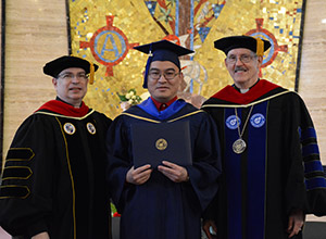 Truong An Nguen receiving his college diploma with dignitaries by his side