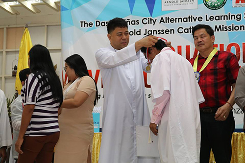 Fr. Jerome Marquez, SVD places a medal on a recent graduate of the Arnold Janssen Mission Foundation