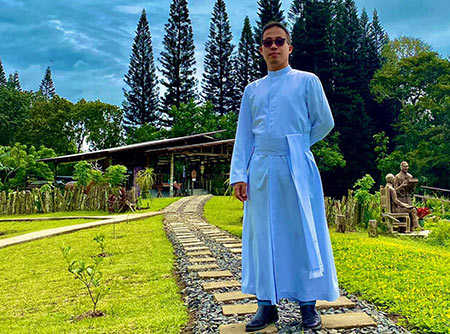 Bro. Mark Paglicawan standing outdoors on a stone path