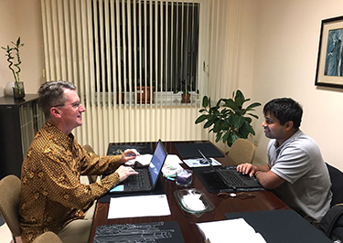 Two men typing on laptop computers at a table 