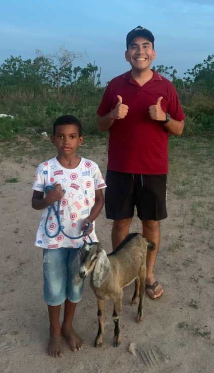 Christian Castro standing next to a young girl and her goat