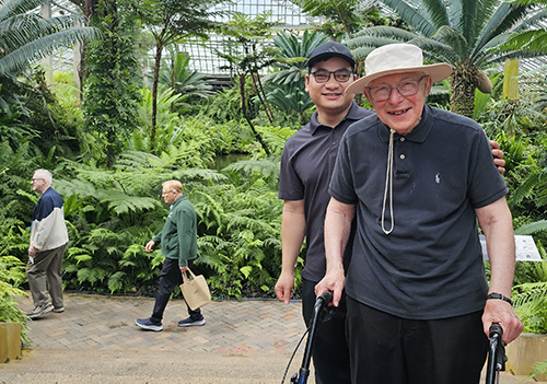 Young and old man in a botanical center amongst bright green foliage