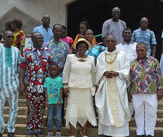 Fr. Pierre in vestments poses with parishioners on church steps