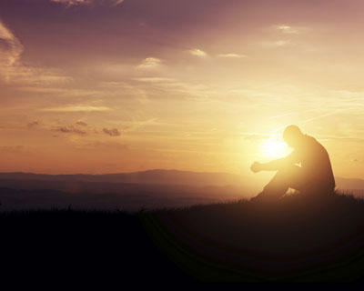 Man in prayer at sunset