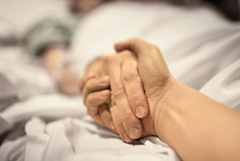 Man's hand holding woman's hand in a hospital room