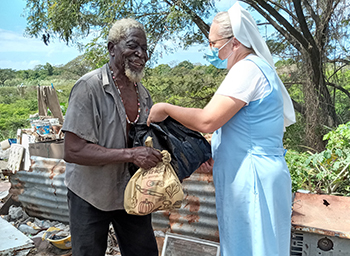 A religious woman handing a bag of food to a poor man