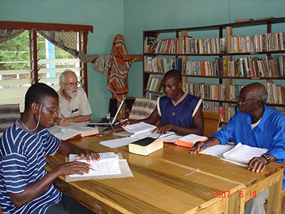 Fr. Fred Timp and three men sit at table translating the bible into local language