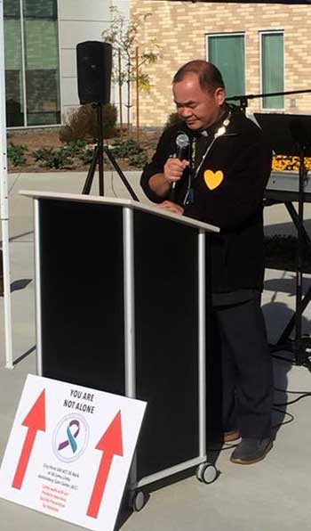 Fr. Ignacio speaking at a podium outdoors
