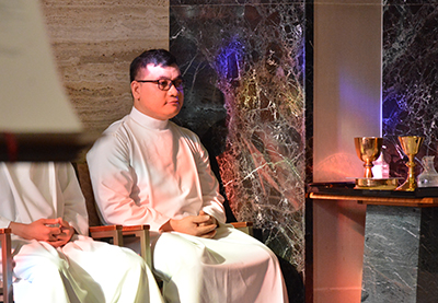 Young Vietnamese man sits silently at the side of an altar