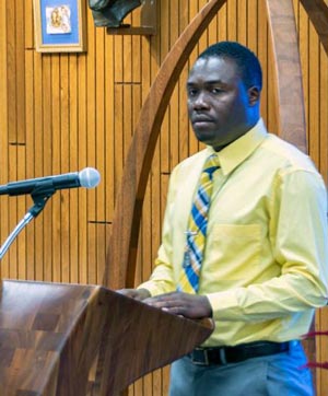 Haitian man in yellow shirt speaking at a podium